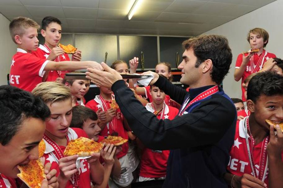 Federer serve la pizza ai ragazzi. AFP